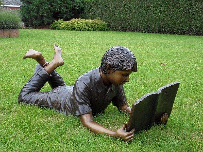 -Bronzefigur Junge am lesen-