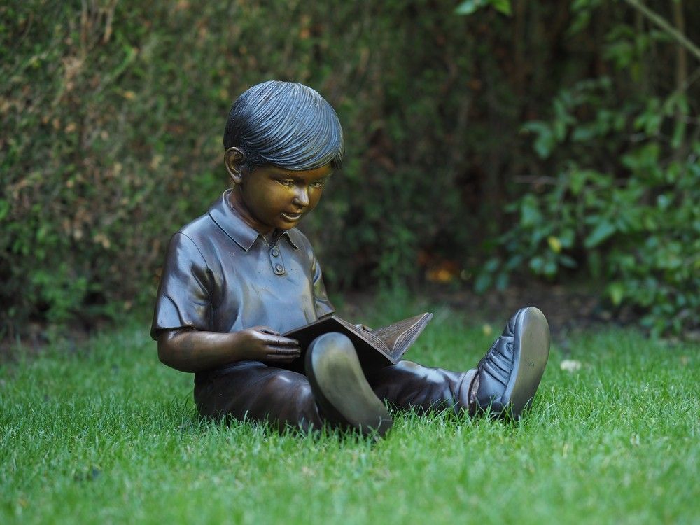-Bronzefigur sitzender Junge mit Buch-