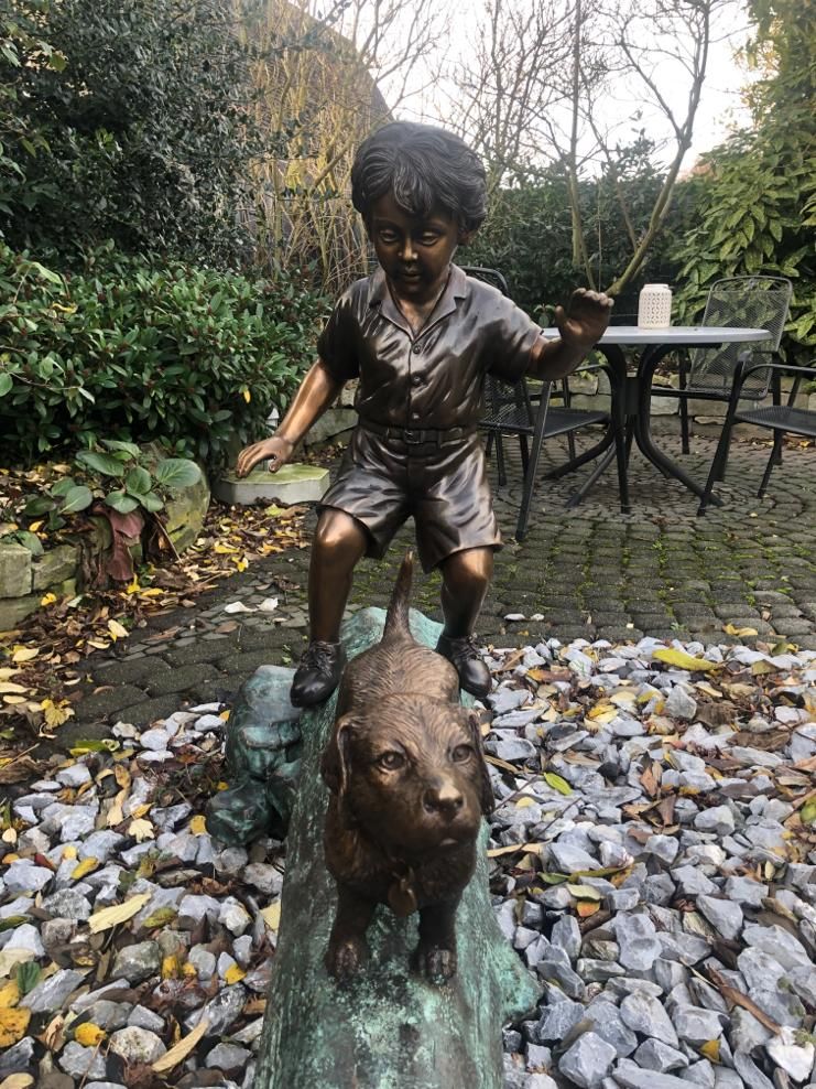 Bronzefigur Junge mit Hund auf Baumstamm